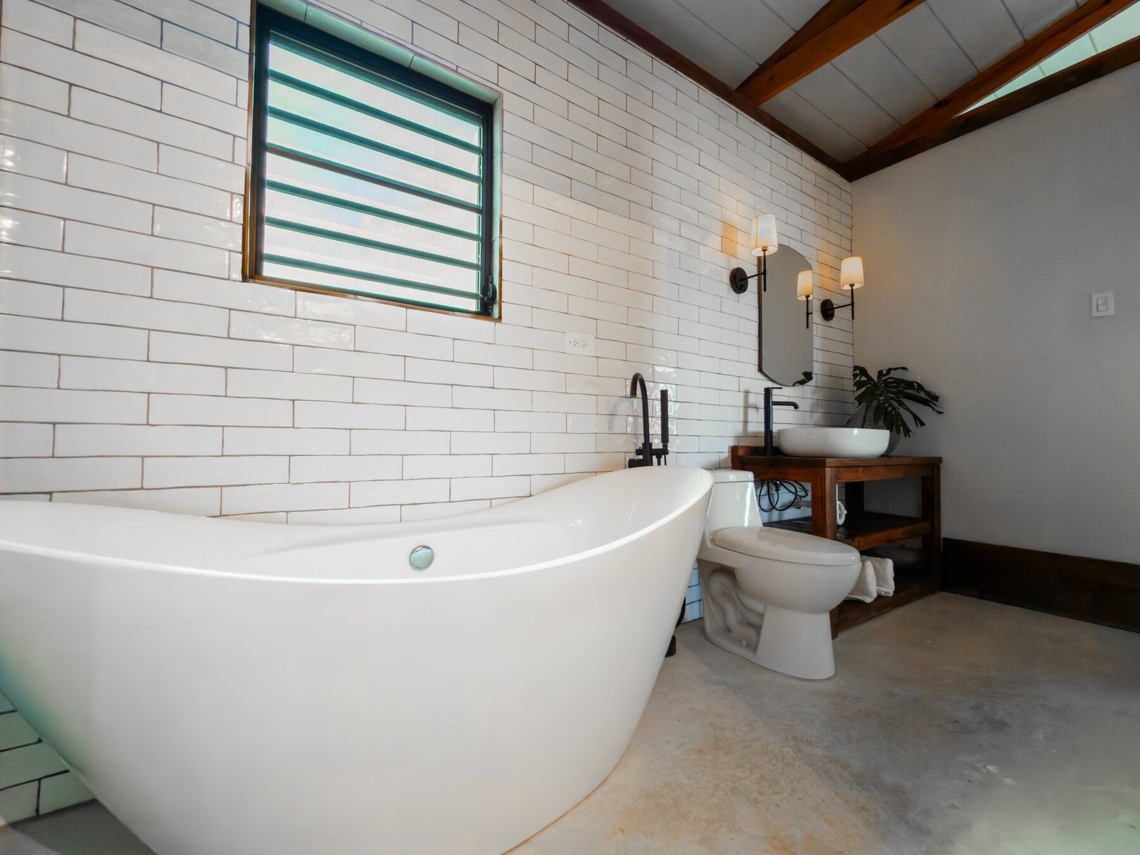 Wide view of the penthouse bathroom with subway tile, tub, and vessel sink vanity