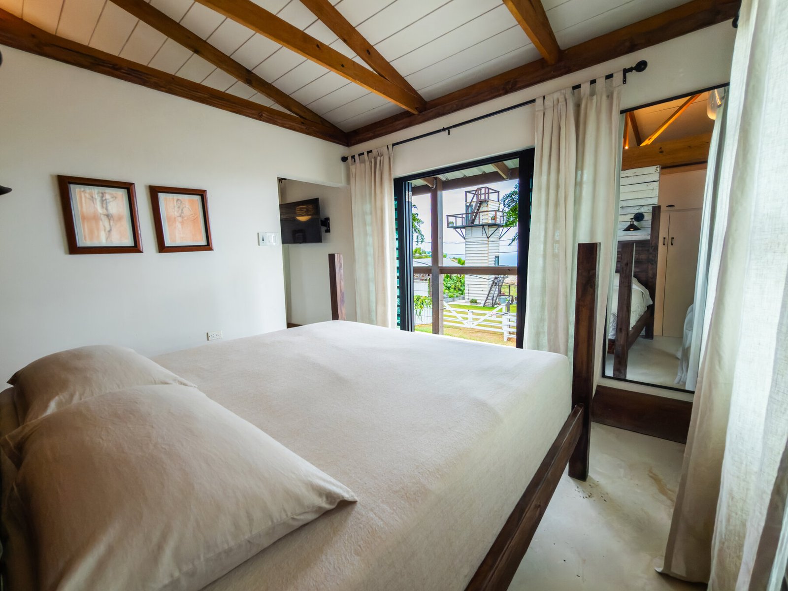 Bedroom with king bed and door open to a porch view of the lookout tower