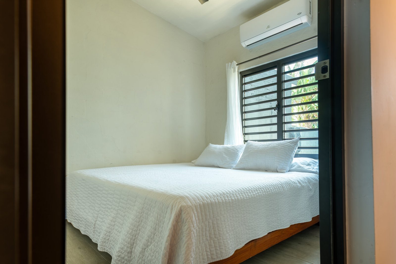 Bedroom with white bedding and A/C